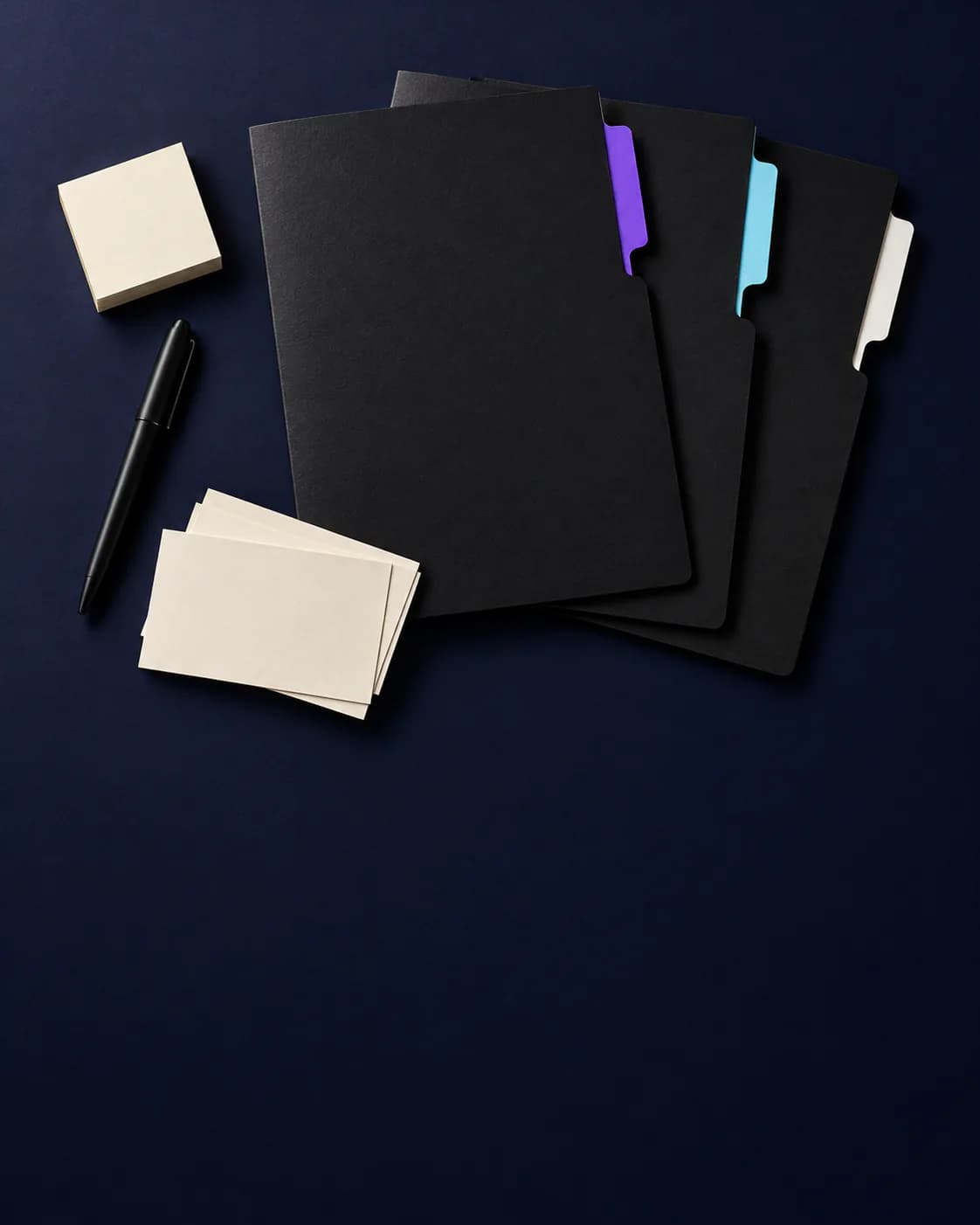Three black document folders with violet, cyan, and white tab dividers beside blank index cards, sticky notes, and a pen on navy