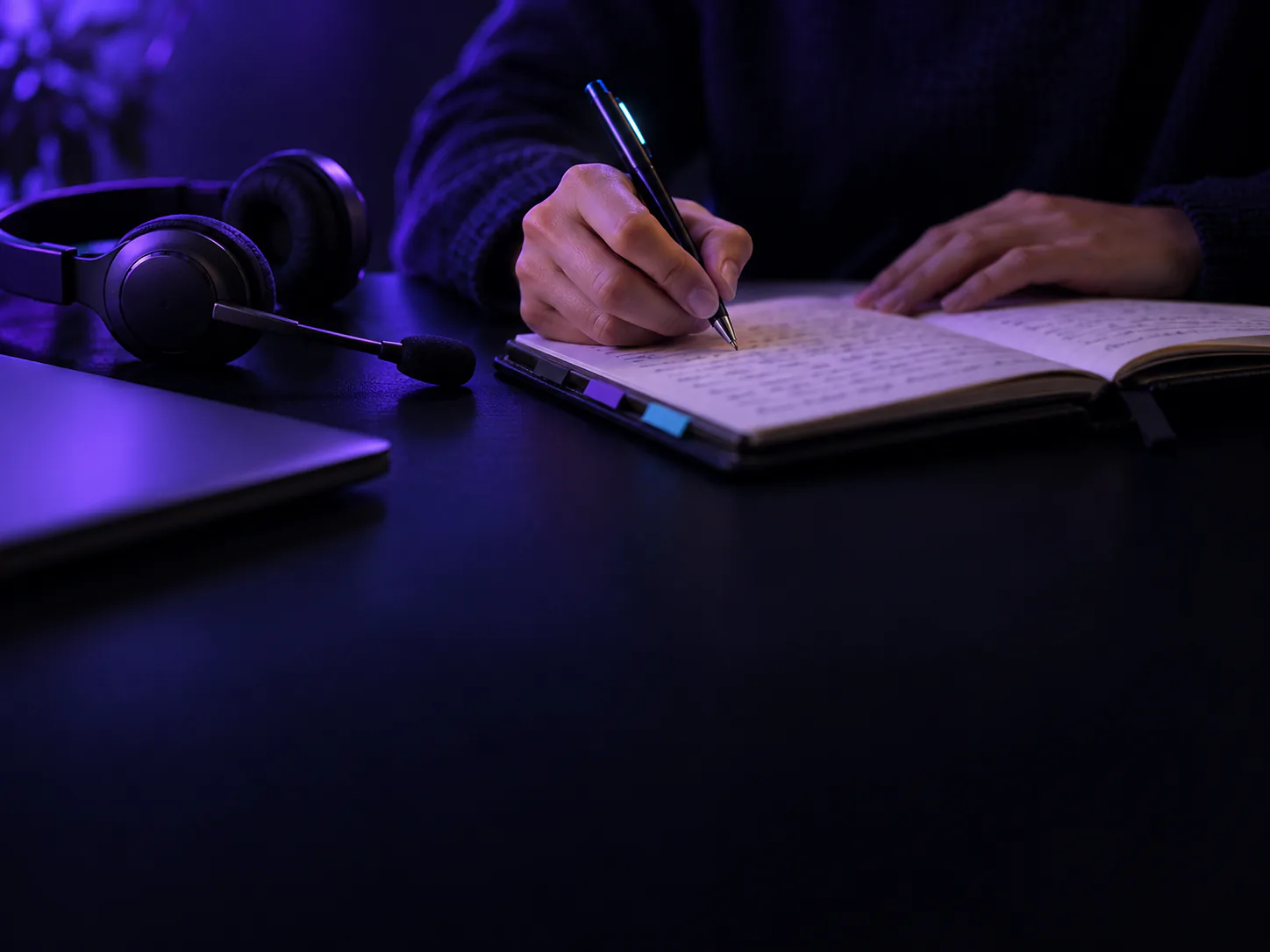 A hand writes a case note in a notebook beside a headset