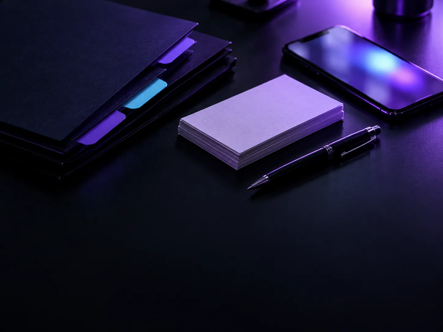 Tabbed folders, a stack of index cards, a pen, and a phone on a dark desk