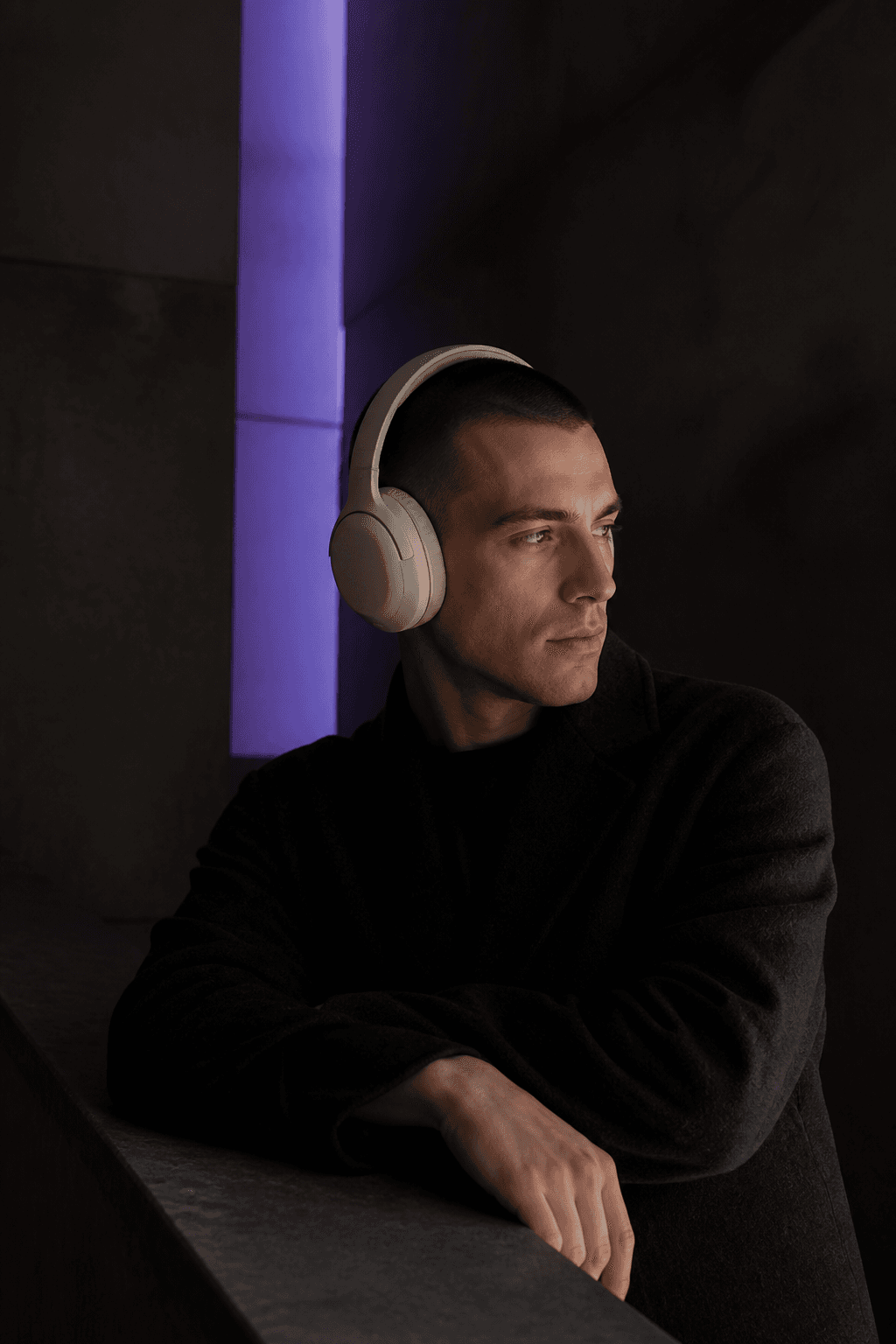 Moody lifestyle photograph of a customer wearing headphones, lit with a violet accent